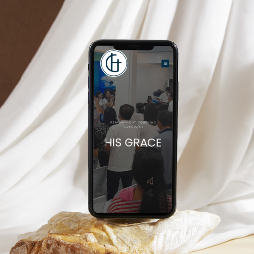 A smartphone showing His Grace Christian Ministries' website
